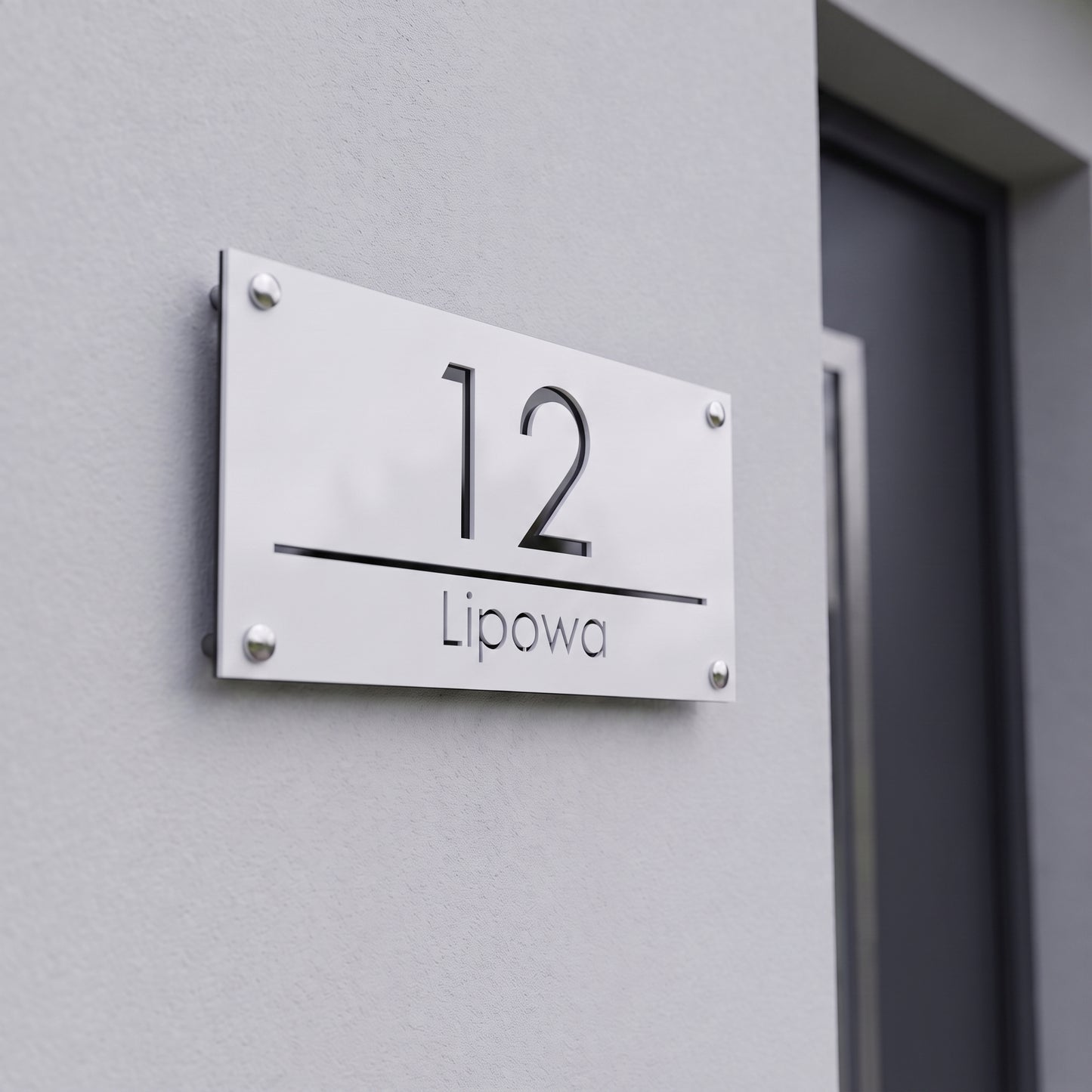 Tabliczka adresowa 3D z numerem 12 i nazwą ulicy Lipowa na jasnej elewacji nowoczesnego domu