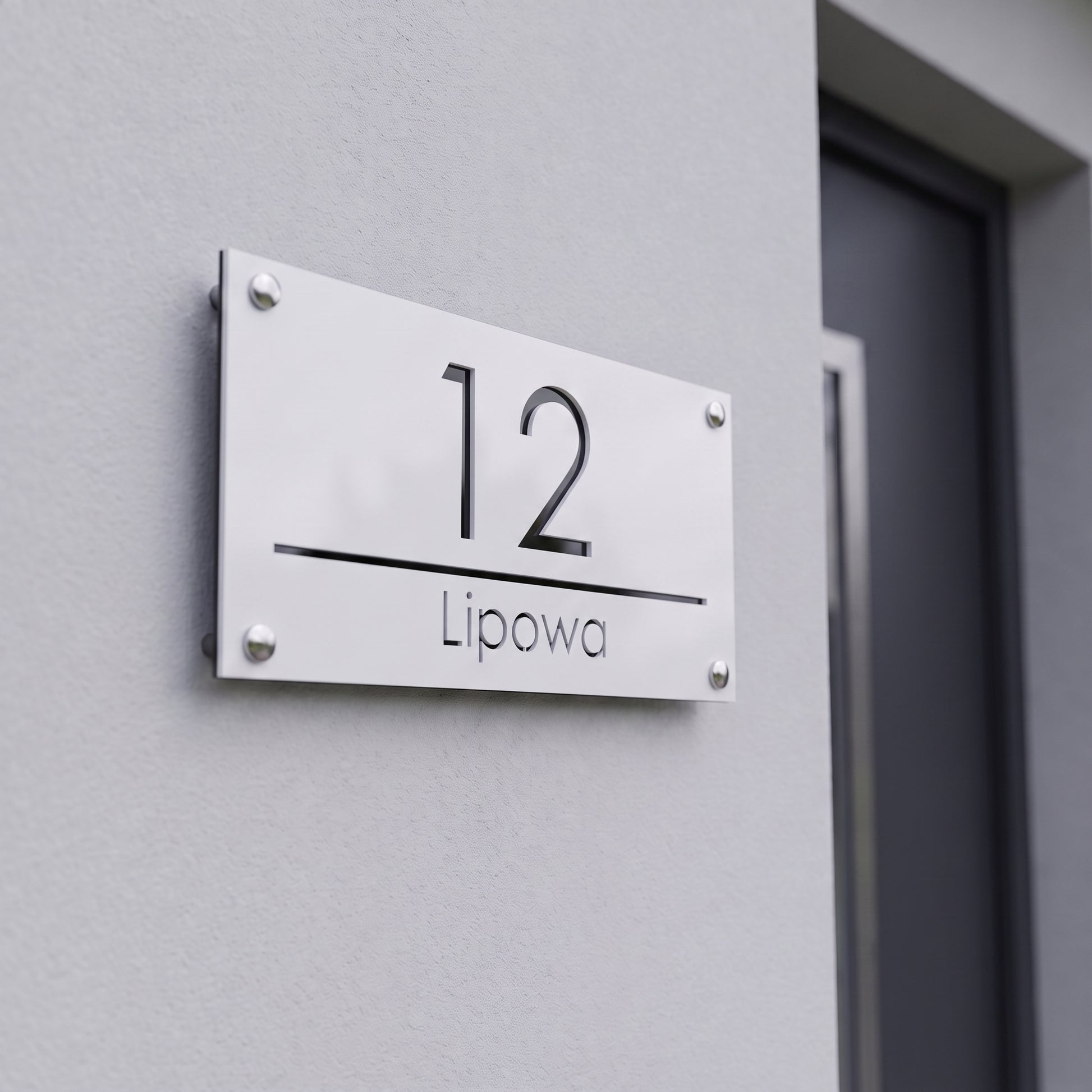 Tabliczka adresowa 3D z numerem 12 i nazwą ulicy Lipowa na jasnej elewacji nowoczesnego domu