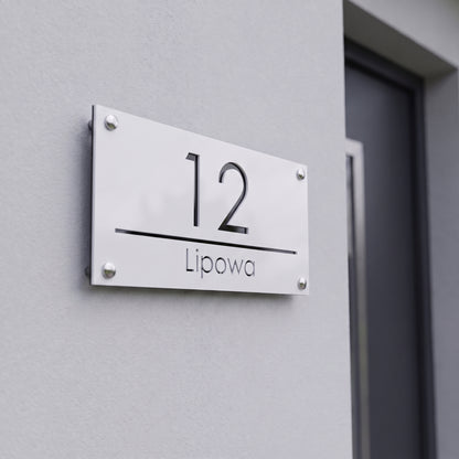 Tabliczka adresowa 3D z numerem 12 i nazwą ulicy Lipowa na jasnej elewacji nowoczesnego domu