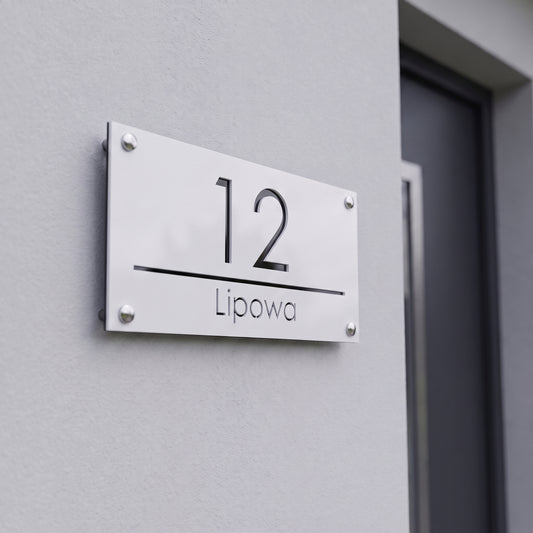 Tabliczka adresowa 3D z numerem 12 i nazwą ulicy Lipowa na jasnej elewacji nowoczesnego domu