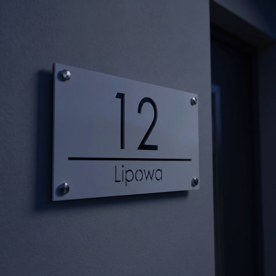 Tabliczka adresowa bez podświetlenia widoczna wieczorem na elewacji domu