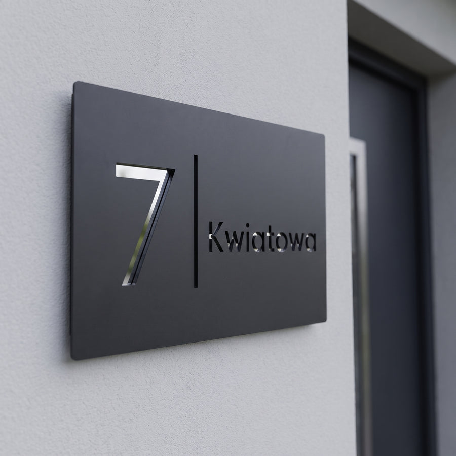 Antracytowa tabliczka adresowa z numerem 7 i nazwą ulicy Kwiatowa z chromowanych cyfr i liter 3D w świetle dziennym