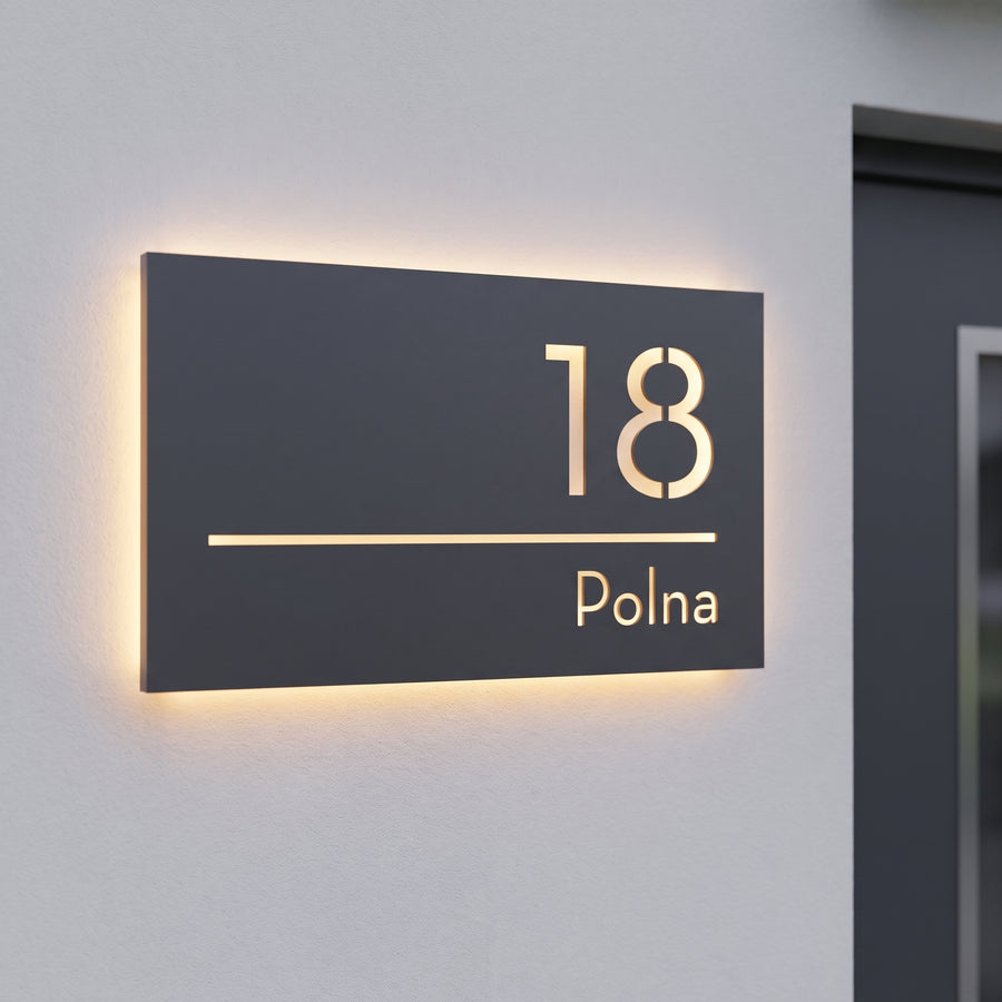Podświetlana tabliczka adresowa LED 12V 18 Polna z ciepłą poświatą halo na jasnoszarej elewacji o zmierzchu